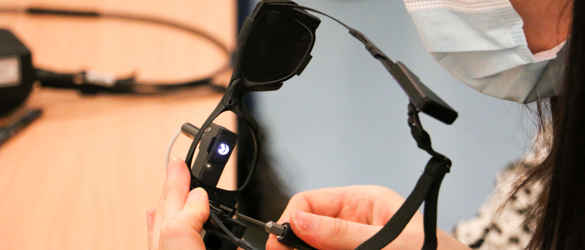 A woman fitting a pair of the black bionic glasses used as part of the PRIMA System