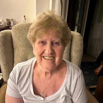 Janet smiling as she sits in her armchair at home