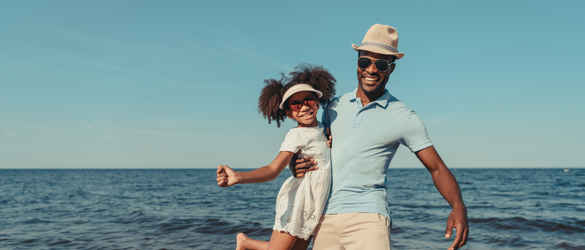 Father and daughter wearing sunglasses on beach