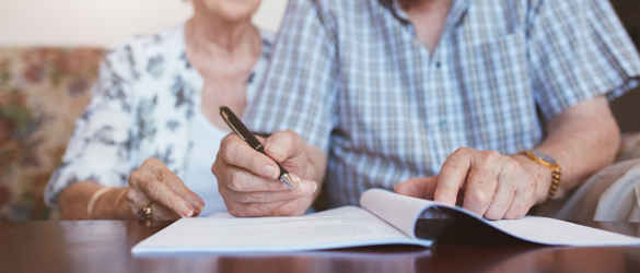 Elderly couple signing documents