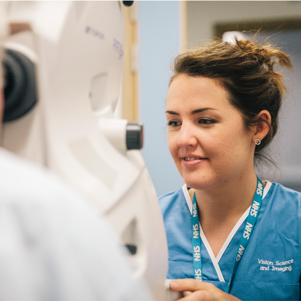 nhs staff looking into eye examination machine